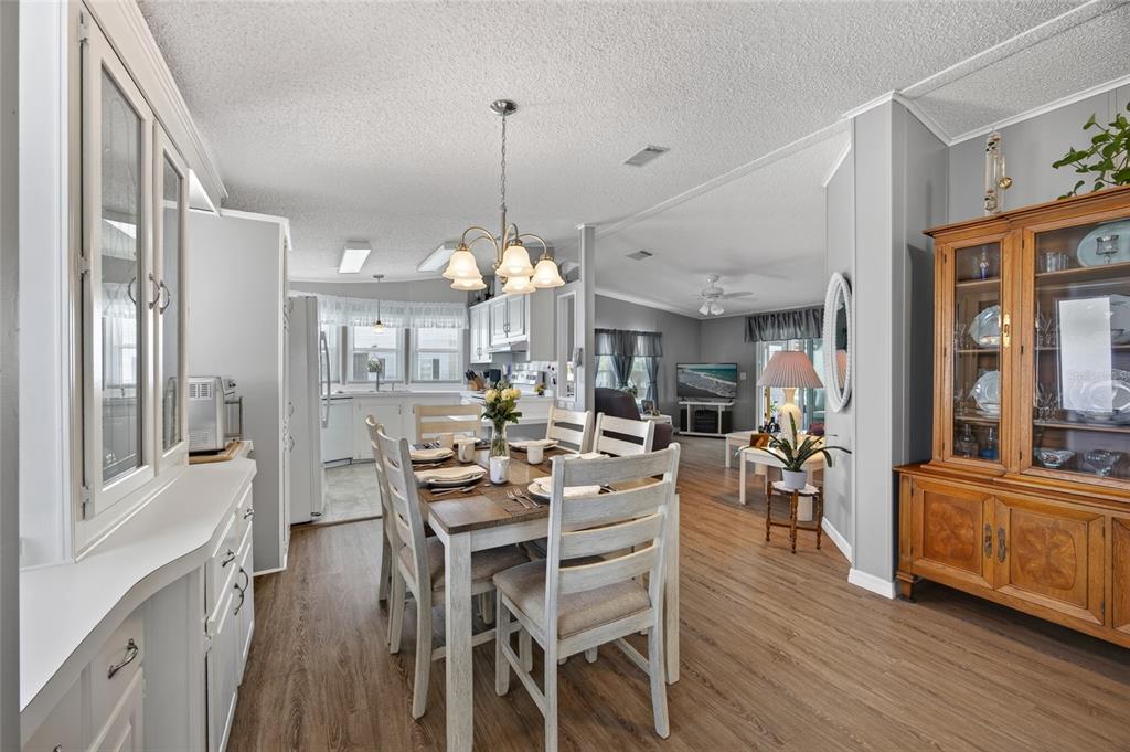 A dining area with a wooden table and chairs, adjacent to a kitchen and living room — 644 SCHOONER STREET, NORTH PORT, FL
