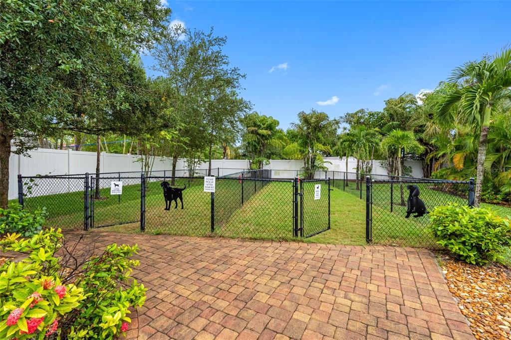 A fenced-in dog park area features a brick paver patio and green grass — 763 DATE PALM LANE, ST PETERSBURG, FL