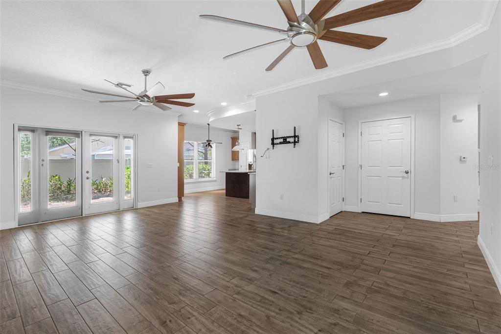 A bright living room features wood-look tile flooring, two ceiling fans, and glass patio doors — 763 DATE PALM LANE, ST PETERSBURG, FL