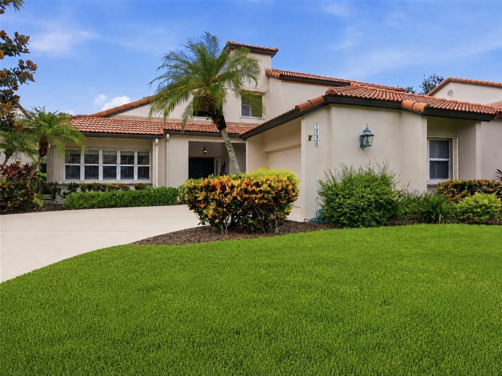 A single-story house with a tile roof, palm tree, and landscaped front yard — 7596 CALLE FACIL, SARASOTA, FL
