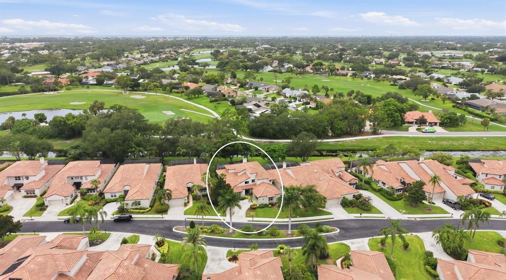 An aerial view of a residential neighborhood featuring a circled house with a tiled roof — 7596 CALLE FACIL, SARASOTA, FL