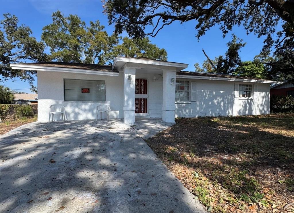A single-story white house with a concrete driveway and a covered front entryway — 2620 E 33RD AVENUE, TAMPA, FL
