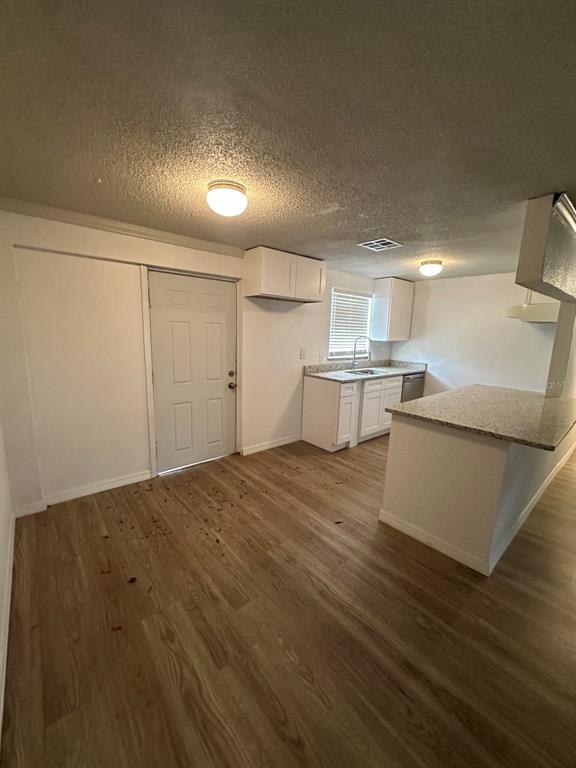 A kitchen with white cabinets, granite countertops, and light wood-look flooring — 2620 E 33RD AVENUE, TAMPA, FL