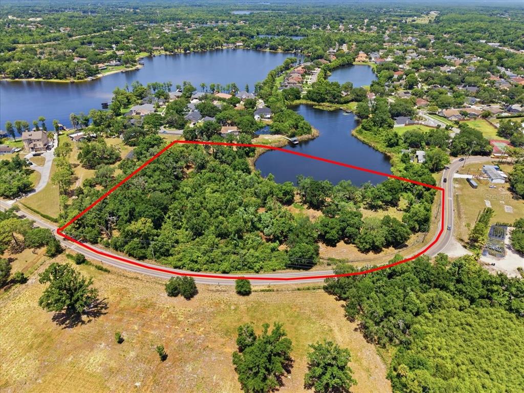 An aerial view shows a wooded, undeveloped lot outlined in red next to a lake — 8901 S MOBLEY ROAD, TAMPA, FL