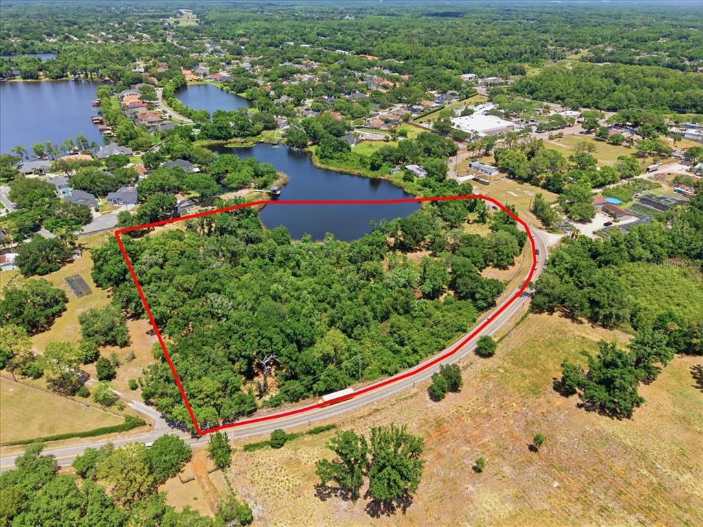 An aerial view shows a wooded plot of land outlined in red next to a lake — 8901 S MOBLEY ROAD, TAMPA, FL