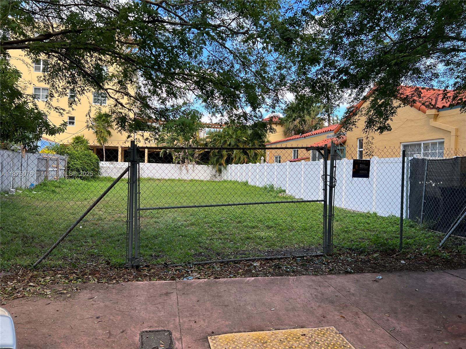 A fenced, vacant grassy lot sits between two buildings under a canopy of trees — 935 2nd St, Miami Beach FL 33139, MIAMI BEACH, FL