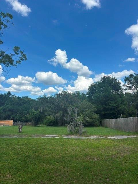 A grassy backyard features a large tree with Spanish moss and a wooden fence — MILDRED AVENUE, BROOKSVILLE, FL