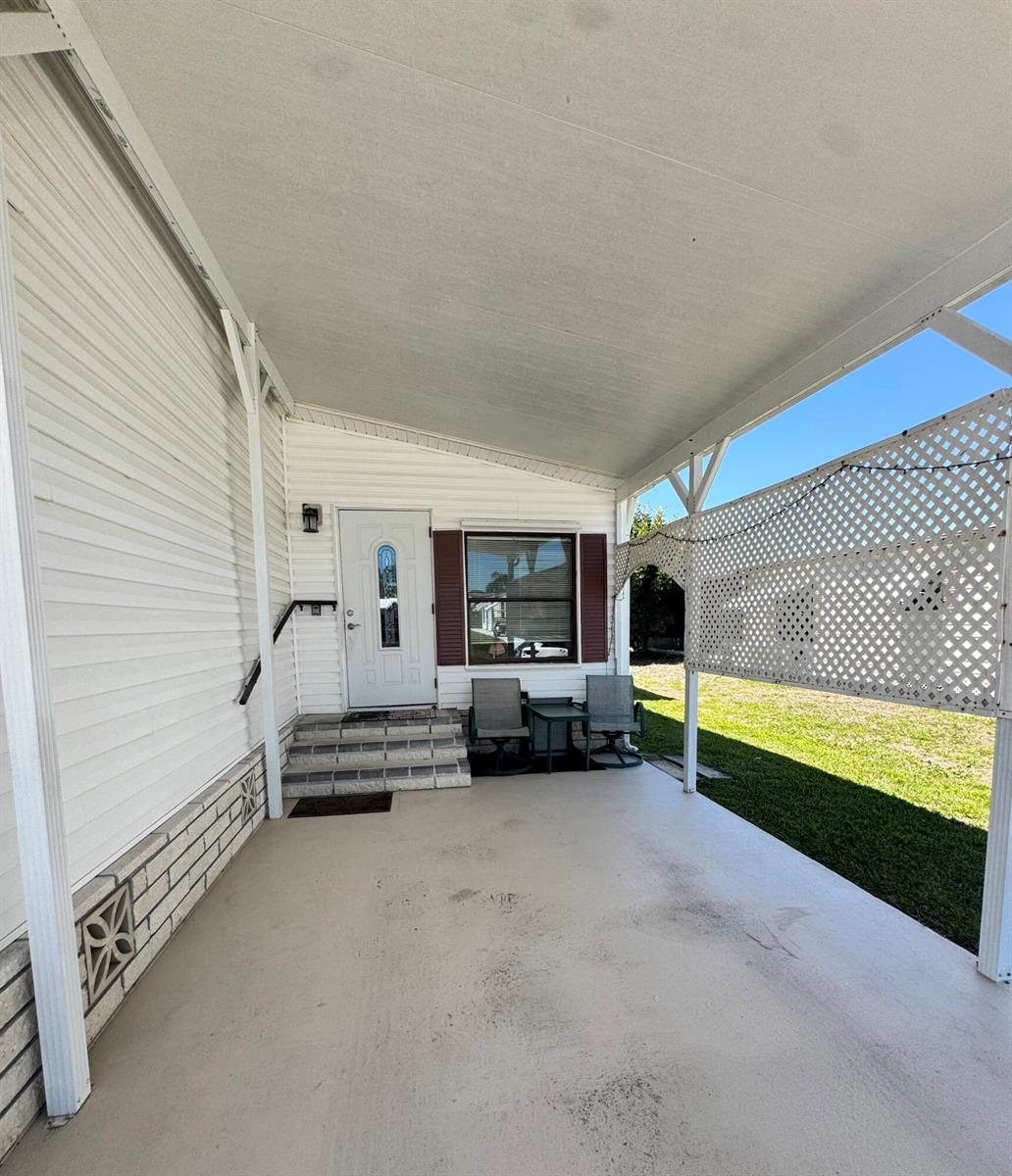 A covered concrete patio features a white front door, steps, and a lattice privacy screen — 37 San Roberto, Fort Pierce FL 34951, FORT PIERCE, FL