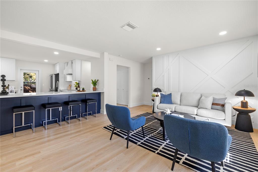 A modern open-concept living room features a blue kitchen island and a white accent wall — 2117 S WEST SHORE BOULEVARD, TAMPA, FL