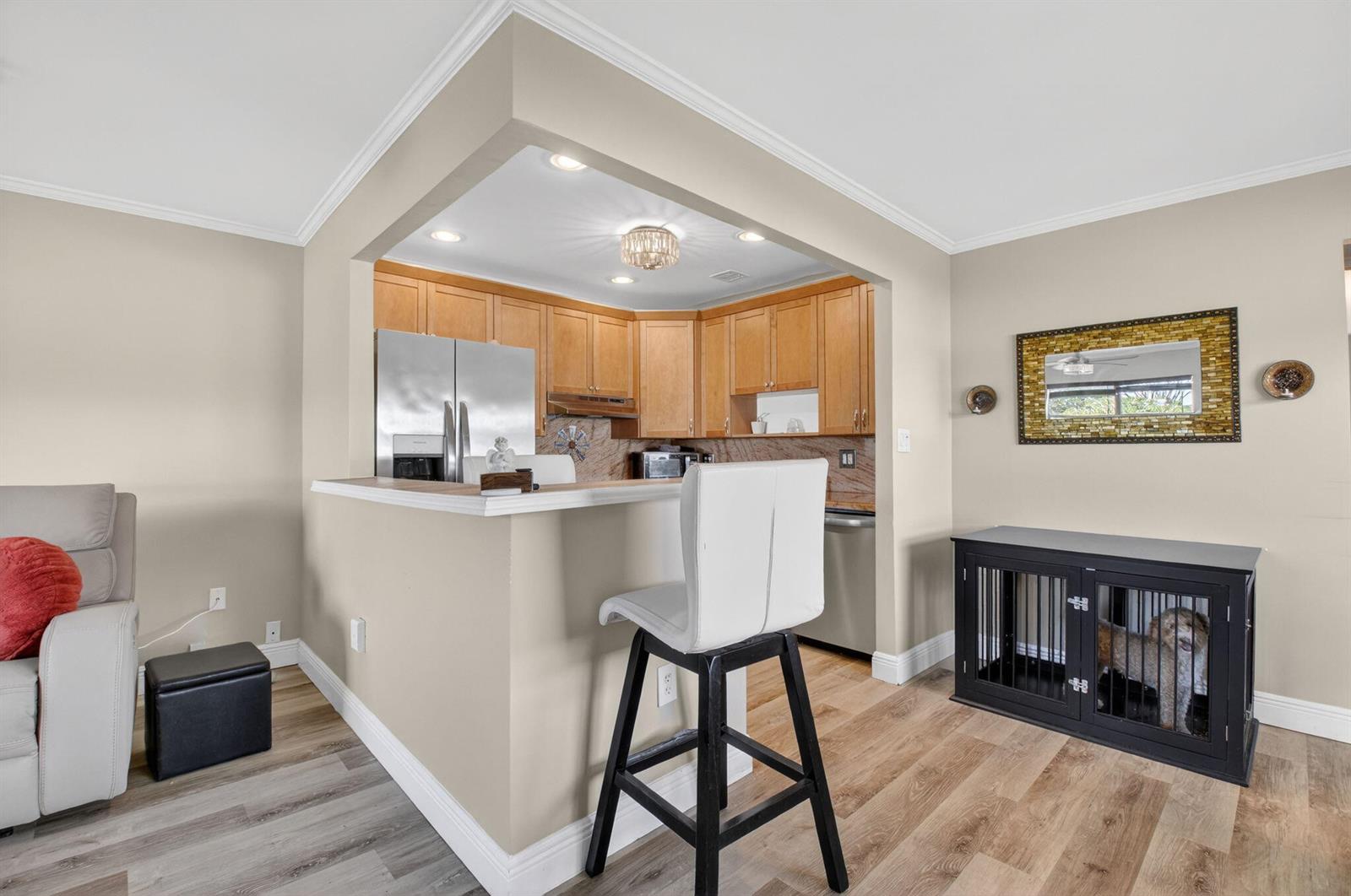 A kitchen with light wood cabinets and a breakfast bar overlooks a living area — 170 Valencia H, Delray Beach FL 33446, DELRAY BEACH, FL