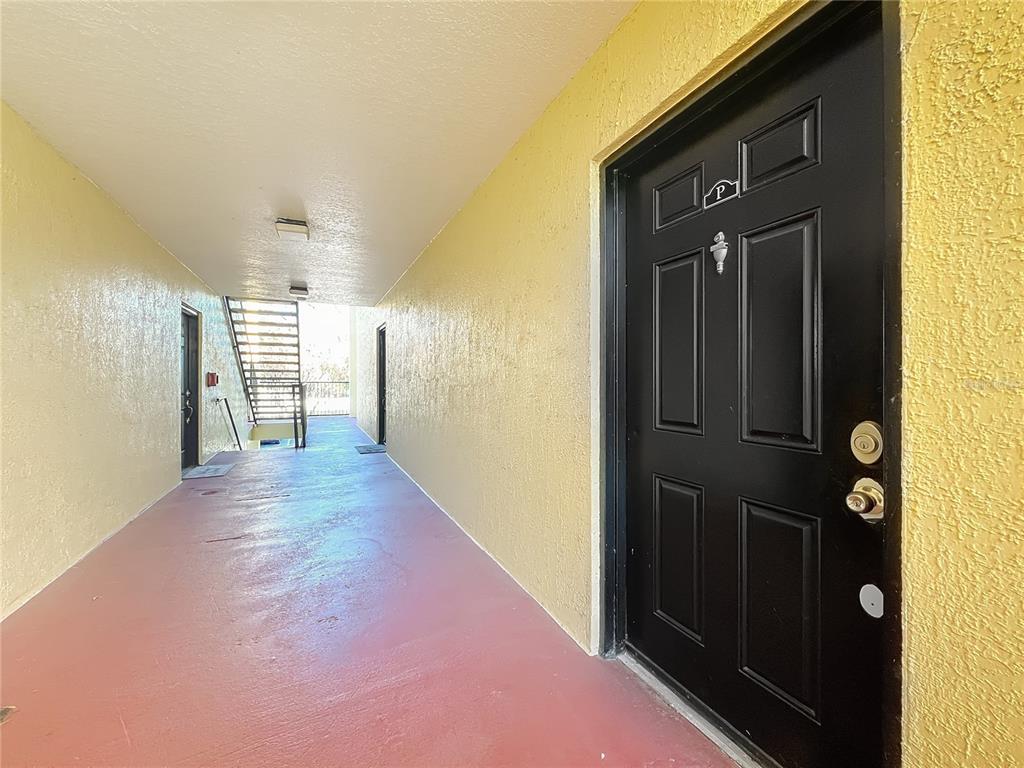 A black front door opens onto a covered exterior walkway with yellow walls and flooring — 2071 DIXIE BELLE DRIVE UNIT 2071P, ORLANDO, FL