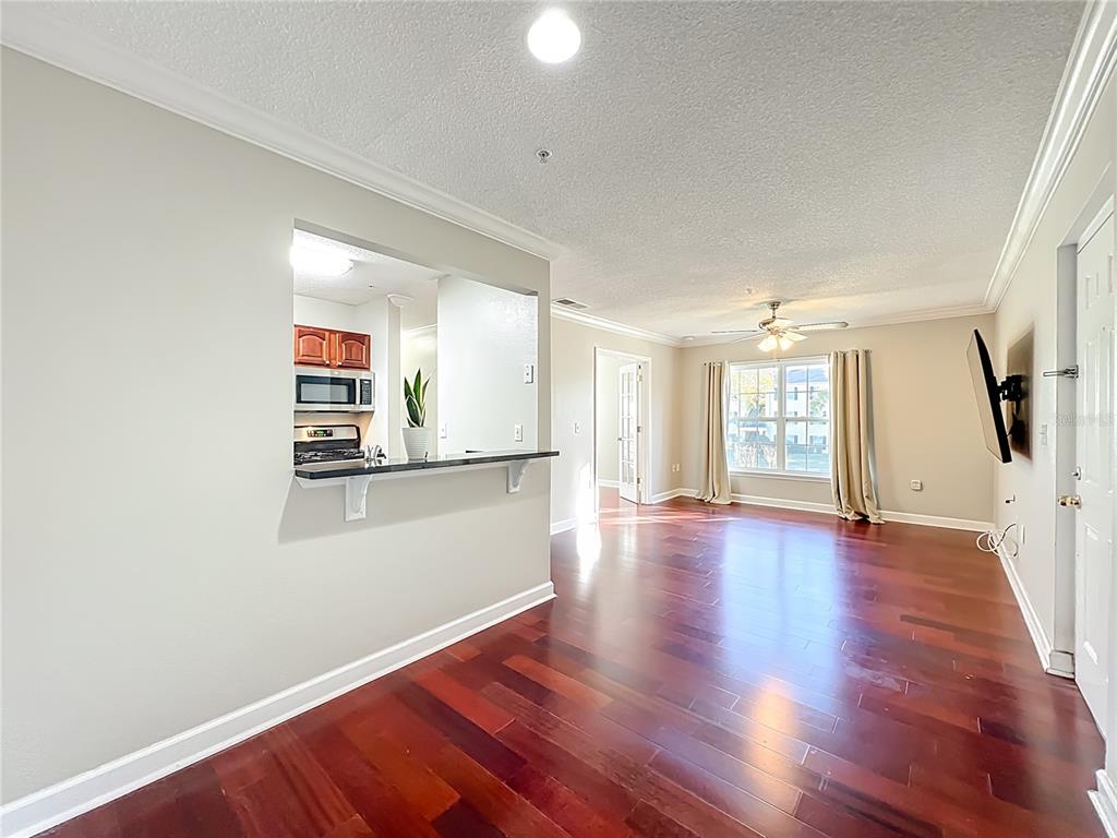 A living room with hardwood floors, a breakfast bar, and a view into the kitchen — 2071 DIXIE BELLE DRIVE UNIT 2071P, ORLANDO, FL