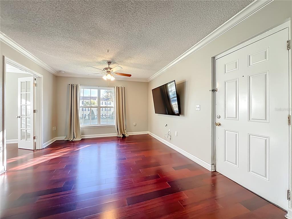A living room features dark hardwood floors, a ceiling fan, and a wall-mounted television — 2071 DIXIE BELLE DRIVE UNIT 2071P, ORLANDO, FL