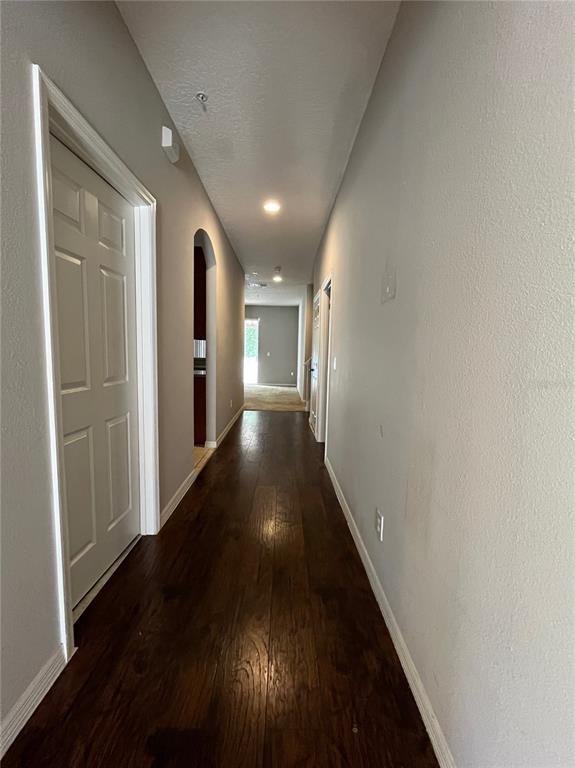 A hallway with dark wood flooring leads toward a bright room in the distance — 10411 KRISTEN PARK DRIVE, ORLANDO, FL