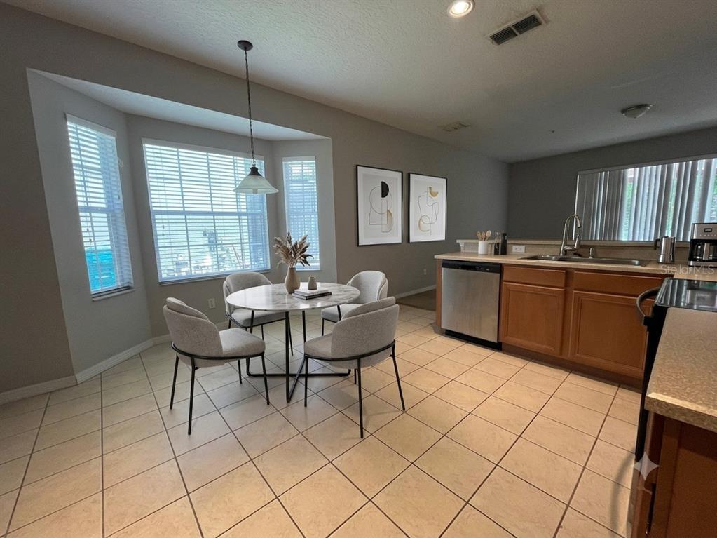 A kitchen with wood cabinets, stainless steel appliances, and an adjacent dining area with windows — 10411 KRISTEN PARK DRIVE, ORLANDO, FL