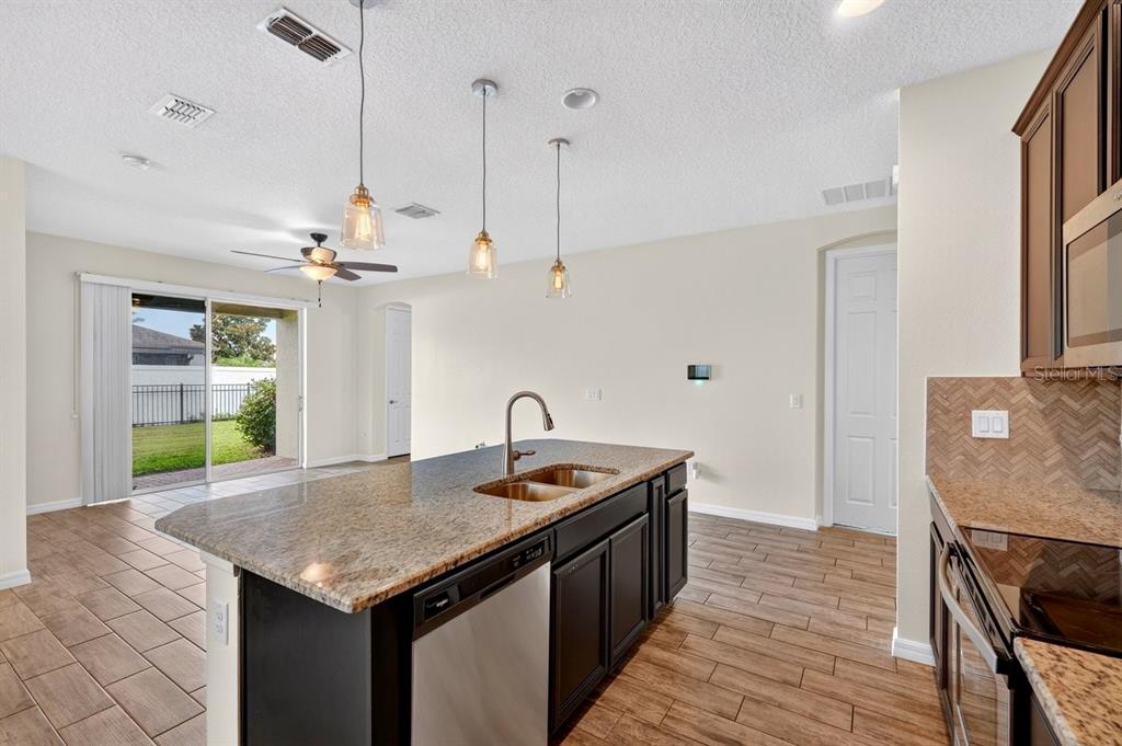 A kitchen island with a granite countertop and sink sits before a sliding glass door — 3833 LOON LANE, SANFORD, FL