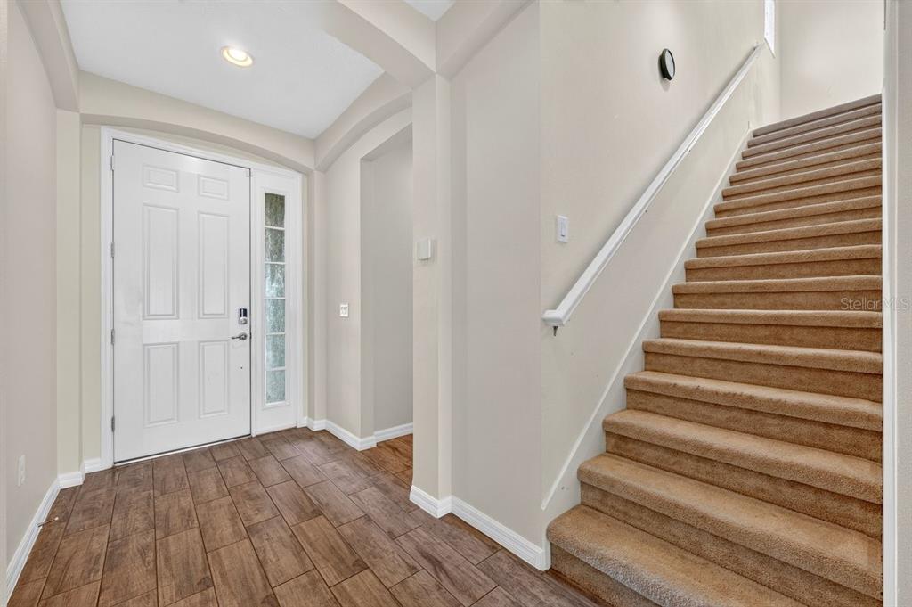 An entryway features wood-look tile flooring, a white front door, and carpeted stairs — 3833 LOON LANE, SANFORD, FL