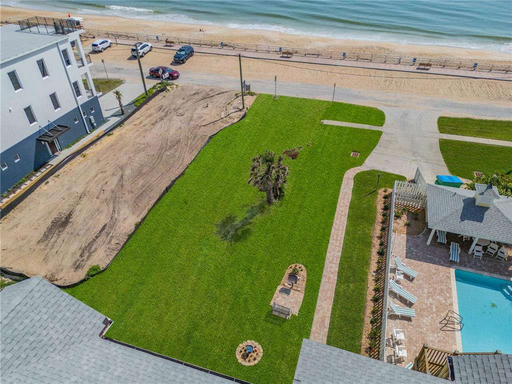 An aerial view shows a grassy lot between a building, a pool area, and the beach — 0 S ATLANTIC AVENUE, NEW SMYRNA BEACH, FL