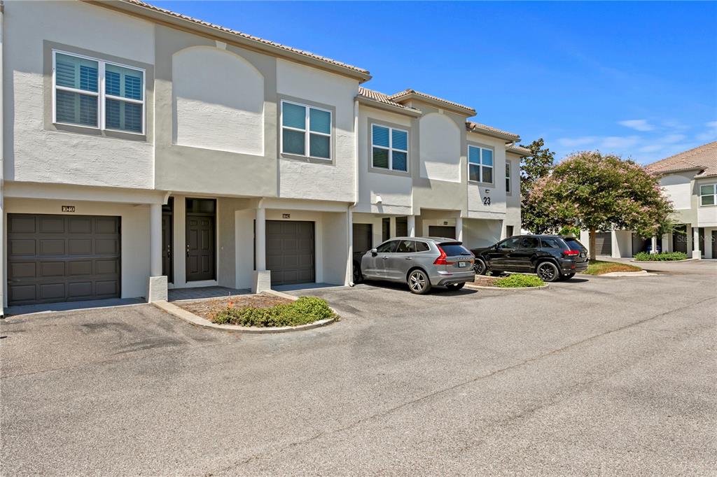 A row of two-story townhomes with garages and parked cars in a paved lot — 1040 NORMANDY TRACE ROAD, TAMPA, FL
