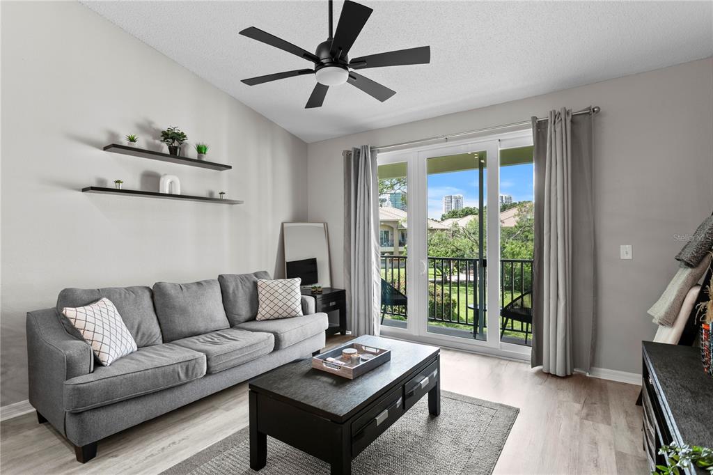 A living room features a gray sofa, a black coffee table, wall shelves, and a balcony — 1040 NORMANDY TRACE ROAD, TAMPA, FL