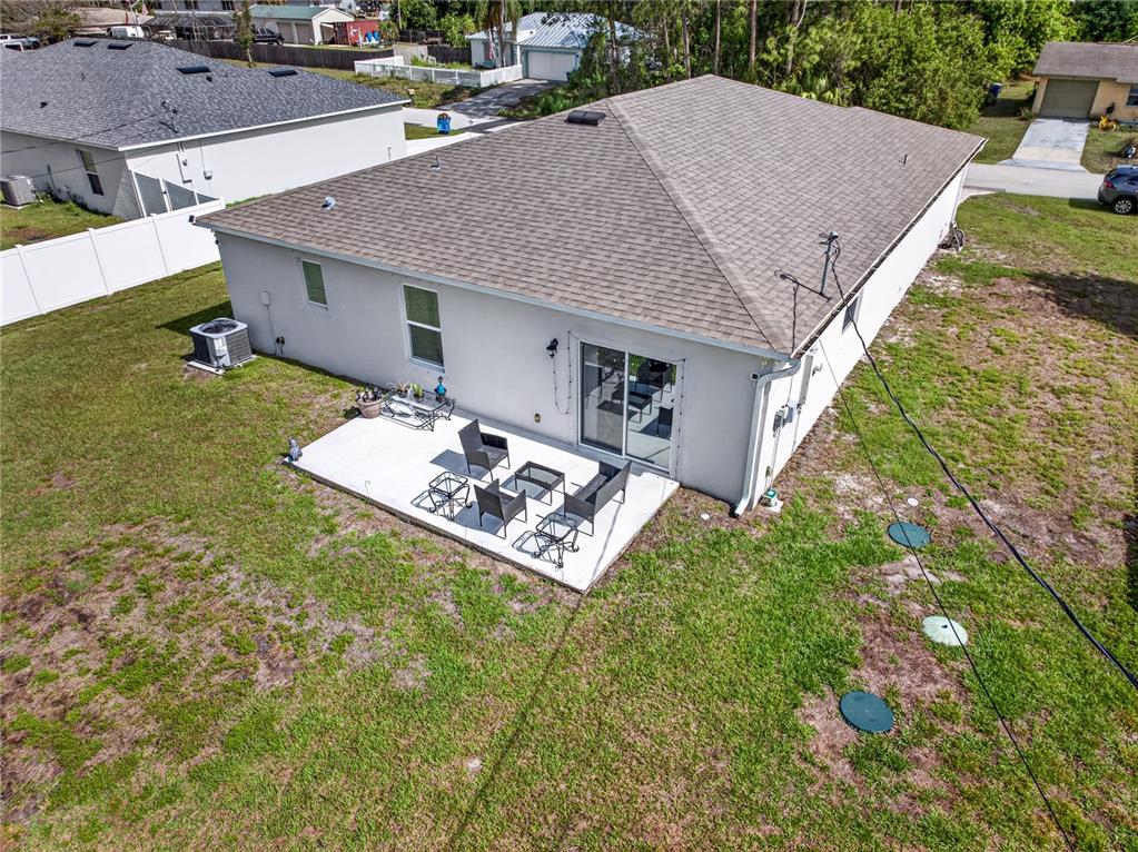 An aerial view of a house exterior featuring a concrete patio and a grassy yard — 180 DOLPHIN STREET SE, PALM BAY, FL