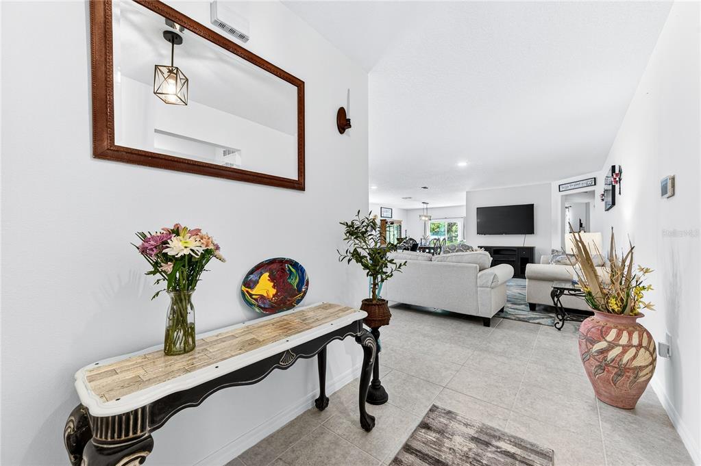 A foyer with a console table and mirror leads into a living room with tile floors — 180 DOLPHIN STREET SE, PALM BAY, FL