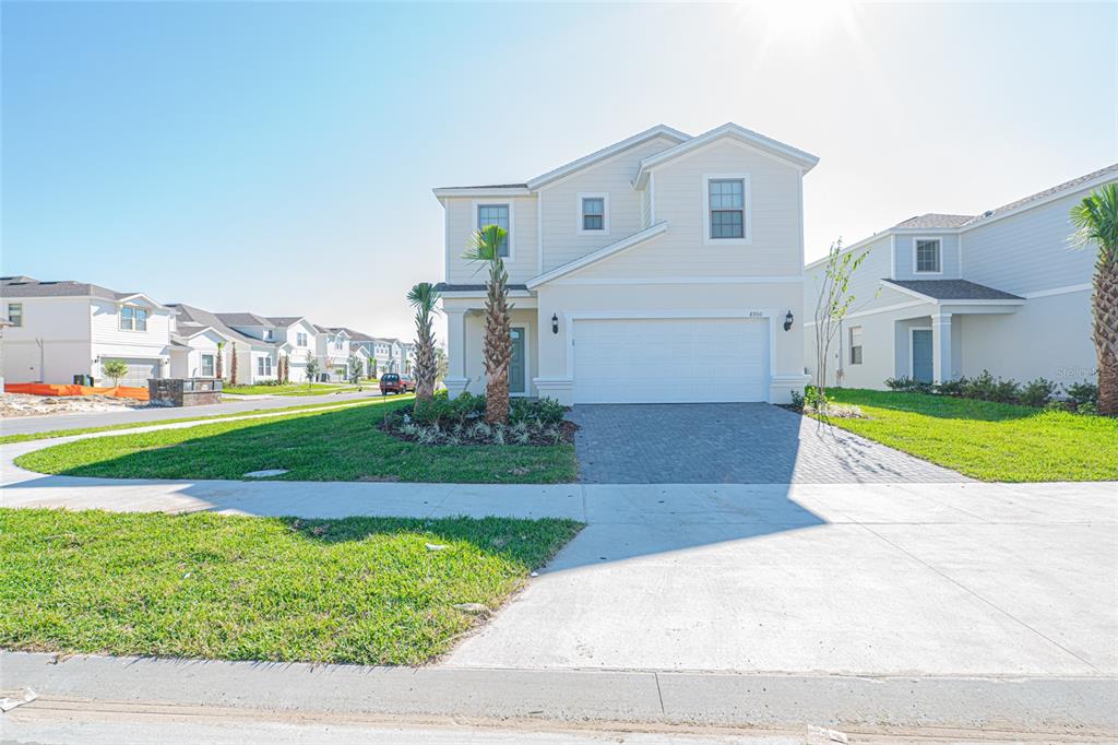 A two-story suburban house with a light-colored exterior, a two-car garage, and palm trees — 8900 PRAGUE WAY, KISSIMMEE, FL