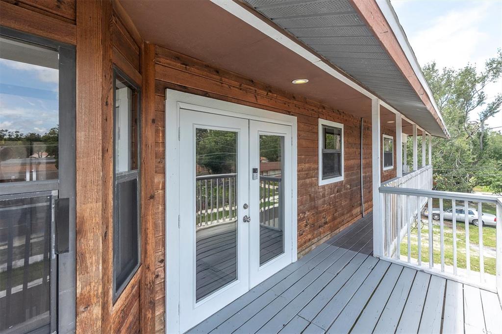 A wooden deck features white French doors, a gray floor, and a white railing — 15590 59TH STREET N, CLEARWATER, FL