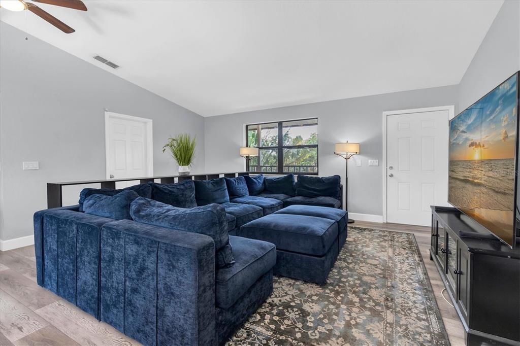 A living room features a large blue sectional sofa, a television, and a patterned rug — 15590 59TH STREET N, CLEARWATER, FL