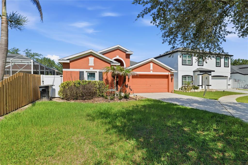 A single-story orange house with a two-car garage sits next to a two-story white house — 704 PARSONS POINTE ST, SEFFNER, FL