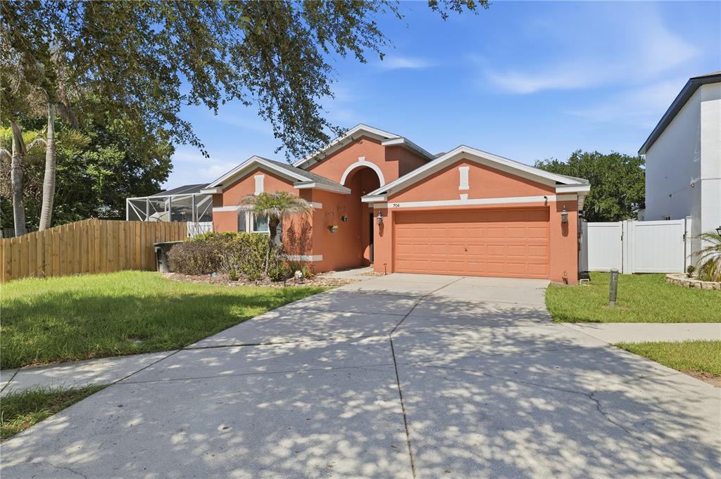 A single-story house with a terracotta-colored exterior, a two-car garage, and a concrete driveway — 704 PARSONS POINTE ST, SEFFNER, FL