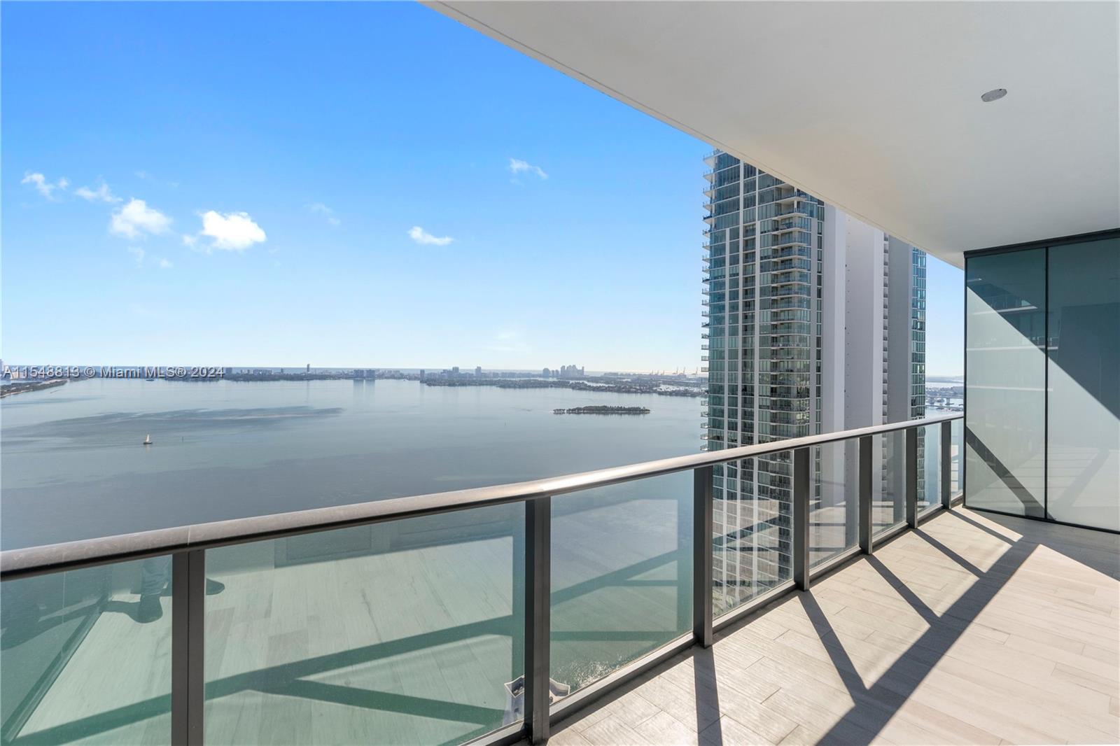 A high-rise balcony features a glass railing overlooking a large bay and city skyline — 480 NE 31st St # 2202, Miami FL 33137, MIAMI, FL