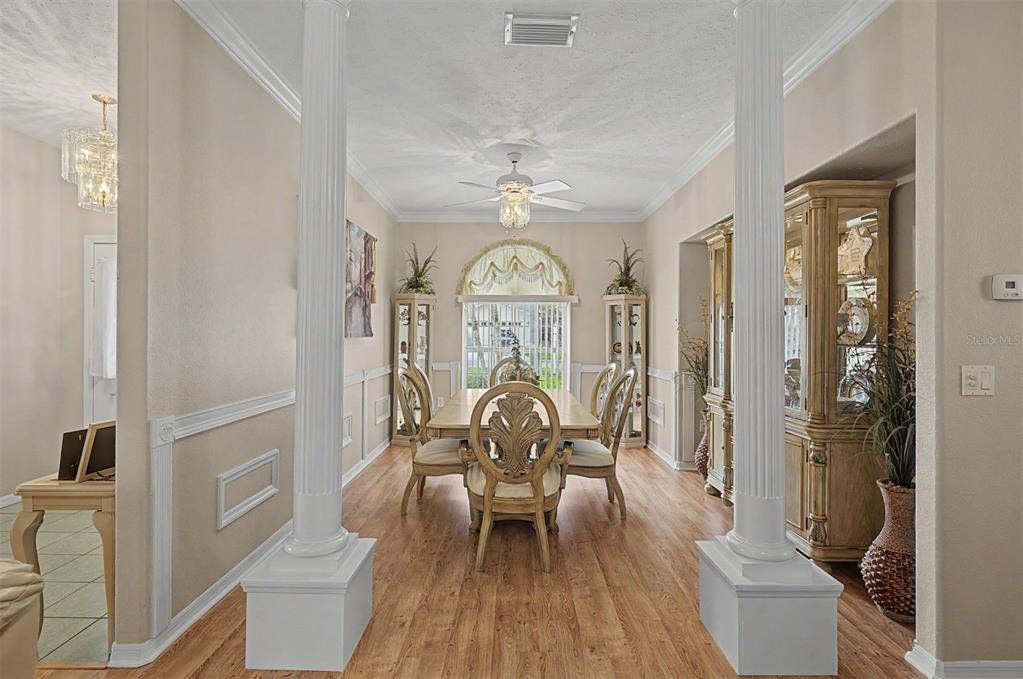 A dining room features a wooden table, chairs, two white columns, and a ceiling fan — 6634 NORTHLAKE DRIVE, ZEPHYRHILLS, FL