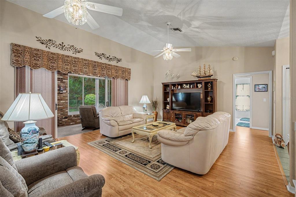 A living room features light wood flooring, vaulted ceilings, two ceiling fans, and leather furniture — 6634 NORTHLAKE DRIVE, ZEPHYRHILLS, FL