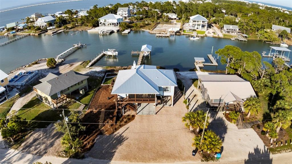 An aerial view shows three houses along a canal with private docks and sandy yards — 331 LAND STREET, EASTPOINT, FL