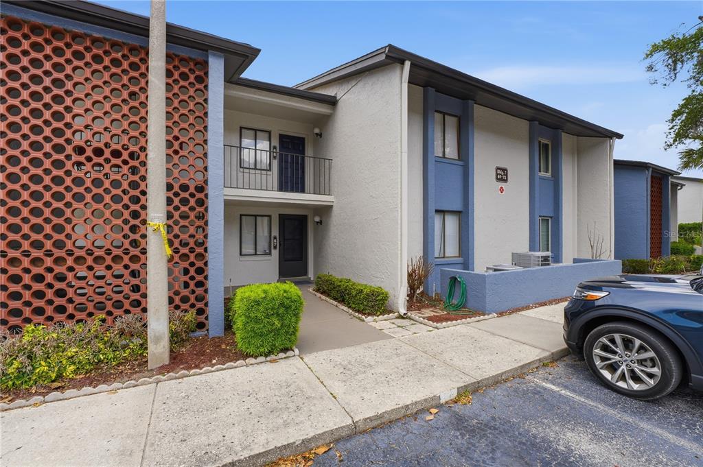 The exterior of a two-story apartment building features a decorative red brick screen wall — 7 ESCONDIDO CIRCLE UNIT 67, ALTAMONTE SPRINGS, FL