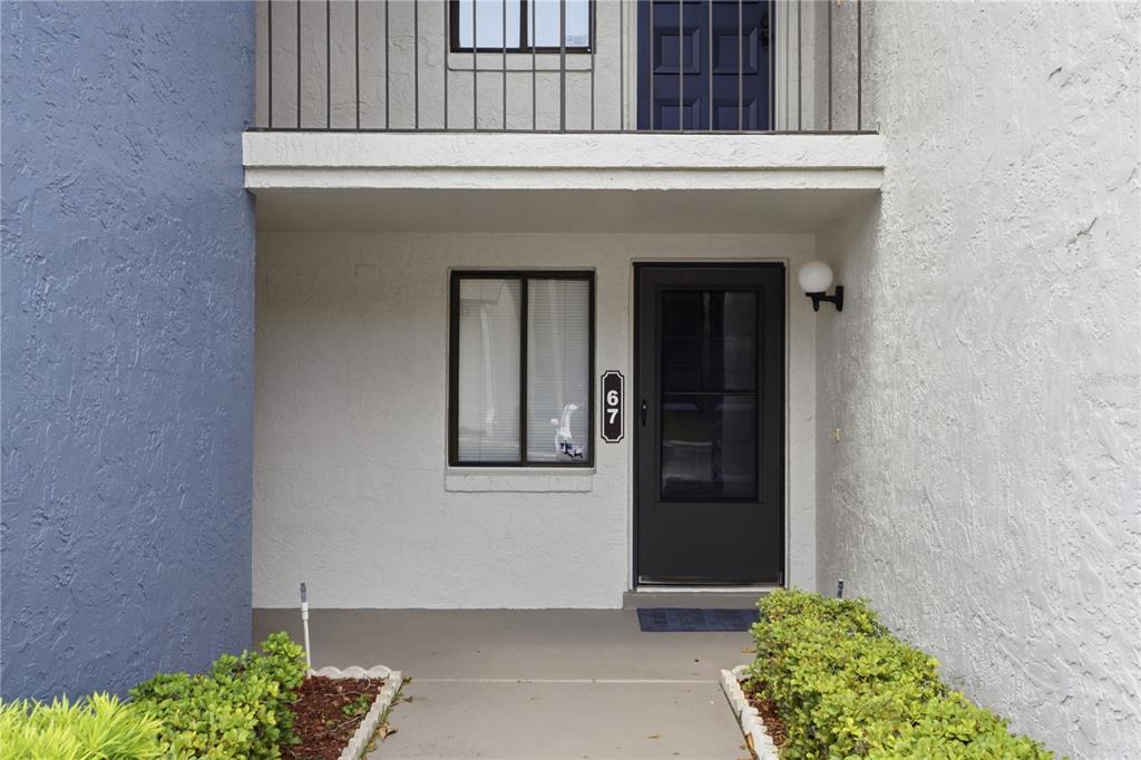 The exterior of a residential unit features a front door, a window, and a balcony — 7 ESCONDIDO CIRCLE UNIT 67, ALTAMONTE SPRINGS, FL