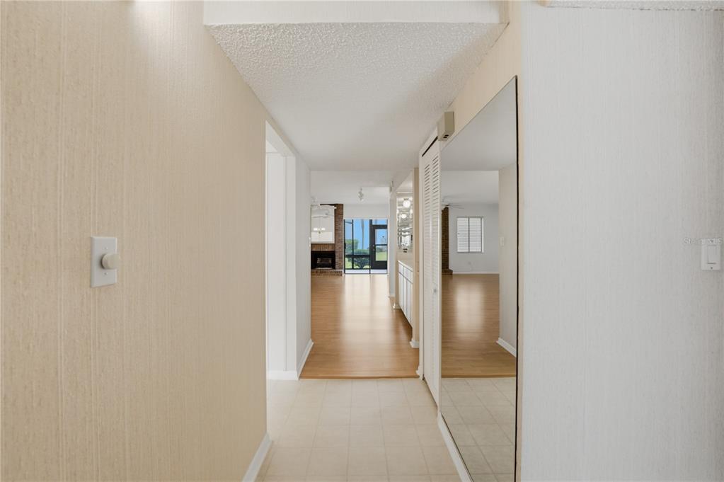 A hallway with tile flooring leads to a living area with wood floors and a fireplace — 7 ESCONDIDO CIRCLE UNIT 67, ALTAMONTE SPRINGS, FL