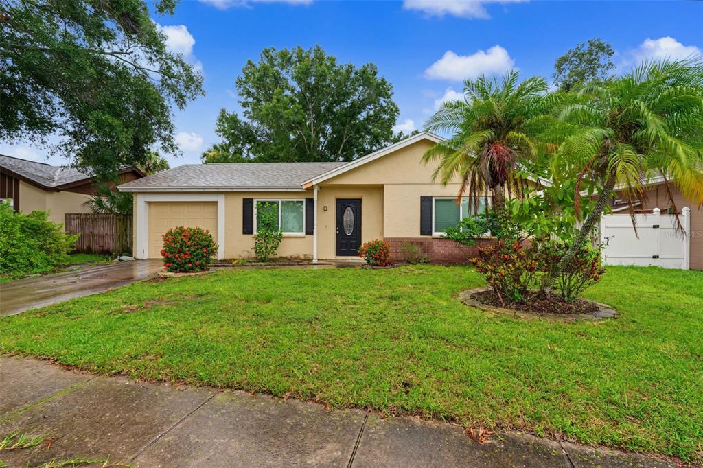A single-story house with a tan stucco exterior, a front-facing garage, and a front lawn — 6470 107TH TERRACE, PINELLAS PARK, FL