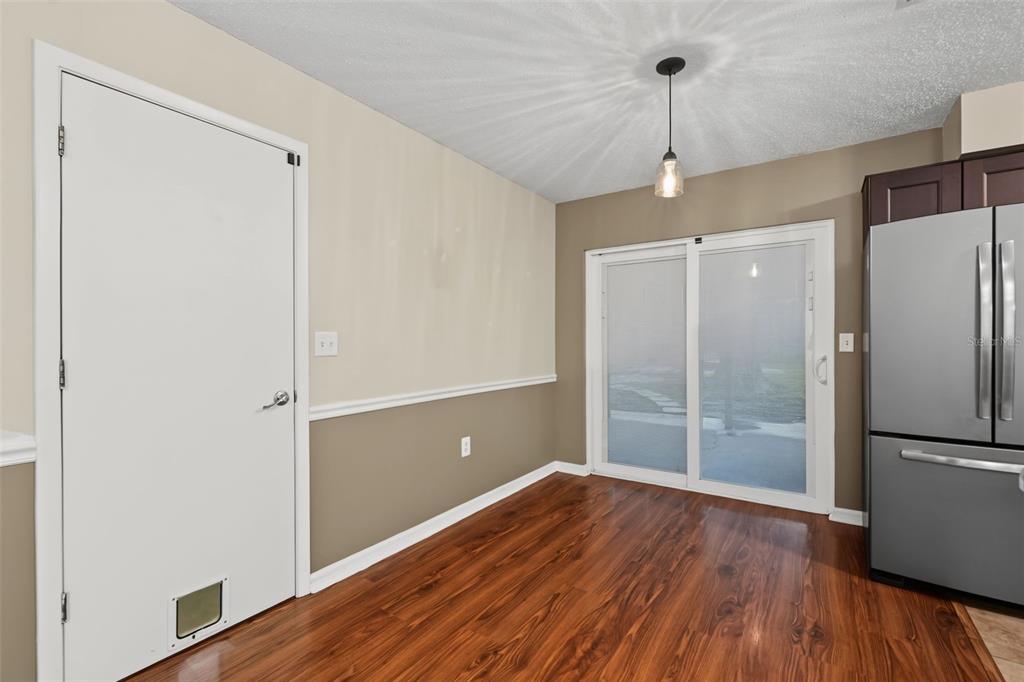 A dining area features wood flooring, two-tone walls, a sliding glass door, and a refrigerator — 6470 107TH TERRACE, PINELLAS PARK, FL
