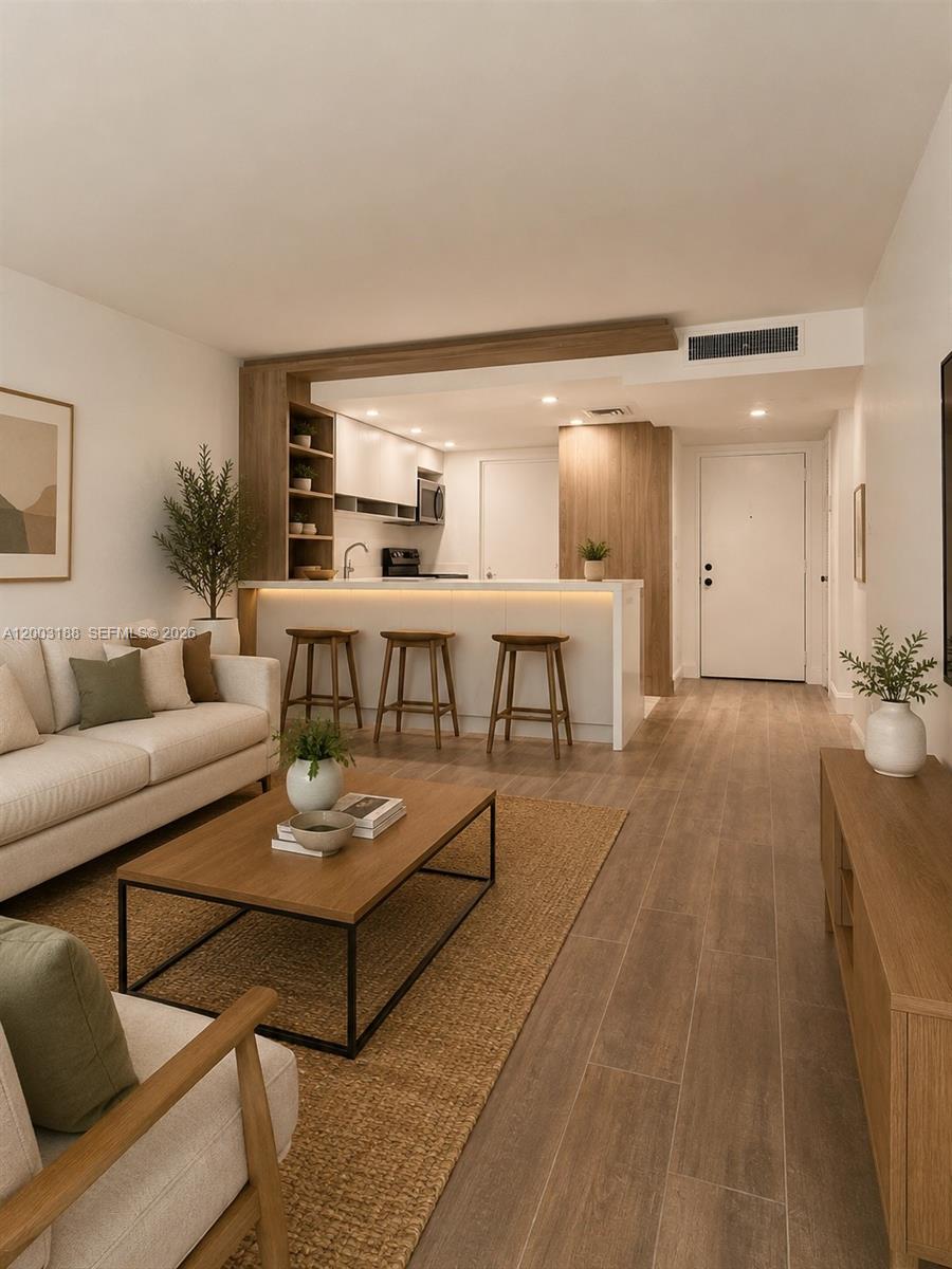 This living room features light wood flooring, a neutral sofa, and an open kitchen bar — 2312 S Cypress Bend Dr # 107, Pompano Beach FL 33069, POMPANO BEACH, FL
