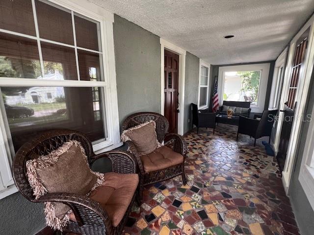 A covered porch features wicker chairs, a mosaic tile floor, and a wooden front door — 4748 7TH AVENUE N, ST PETERSBURG, FL