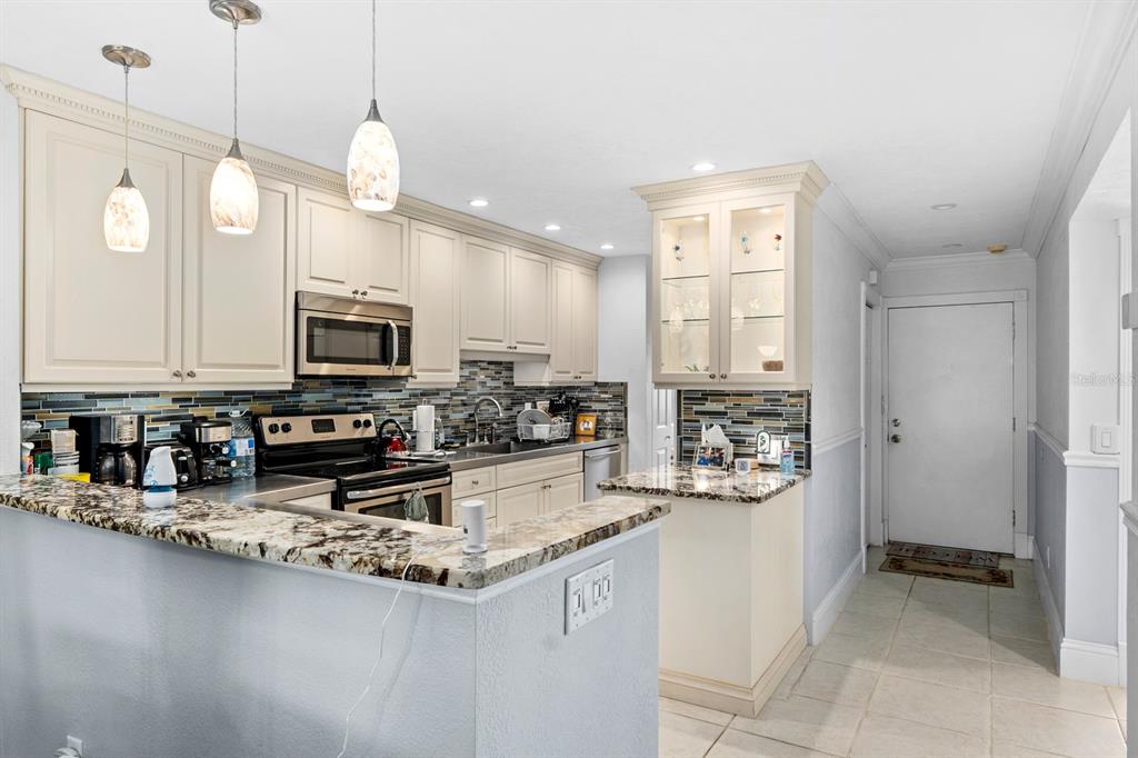 A kitchen features cream cabinets, granite countertops, a glass tile backsplash, and stainless steel appliances — 816 BAHIA DEL SOL DRIVE UNIT 23, RUSKIN, FL