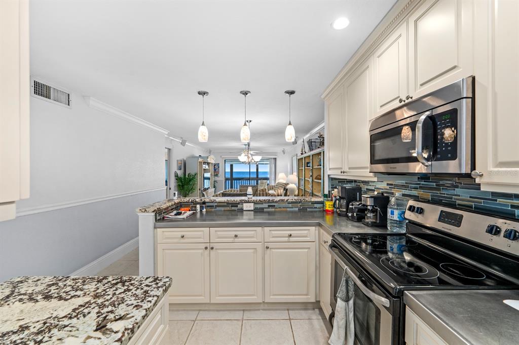 A kitchen with white cabinets, granite countertops, and a view of the ocean beyond — 816 BAHIA DEL SOL DRIVE UNIT 23, RUSKIN, FL