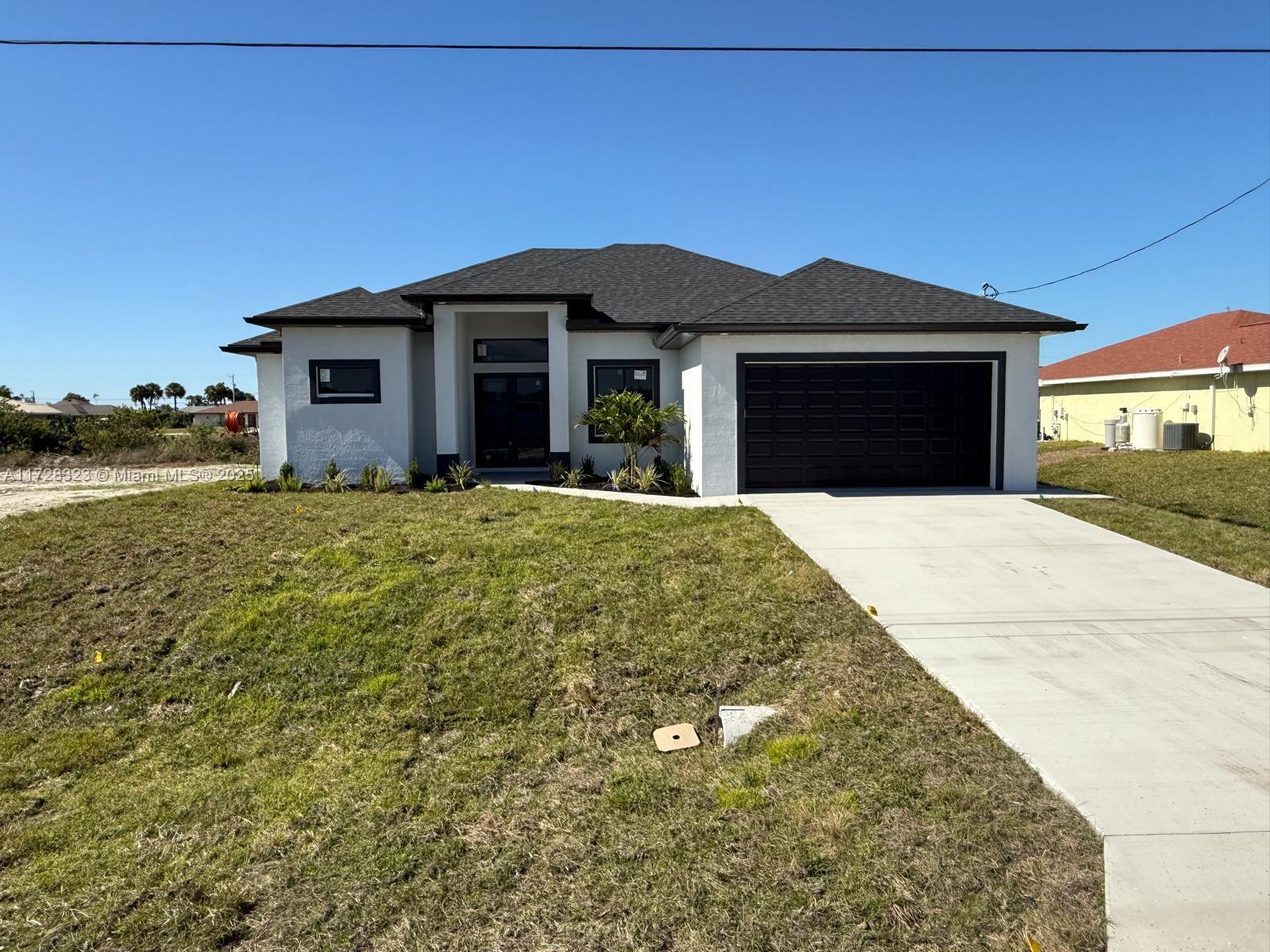 A single-story house with white stucco walls, a dark roof, and a two-car garage — 1320 NE 14th  AVE, Cape Coral FL 33909, CAPE CORAL, FL