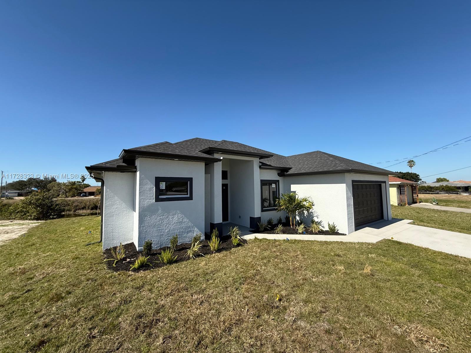 A modern, white single-story house with a dark roof and a front-facing garage — 1320 NE 14th  AVE, Cape Coral FL 33909, CAPE CORAL, FL