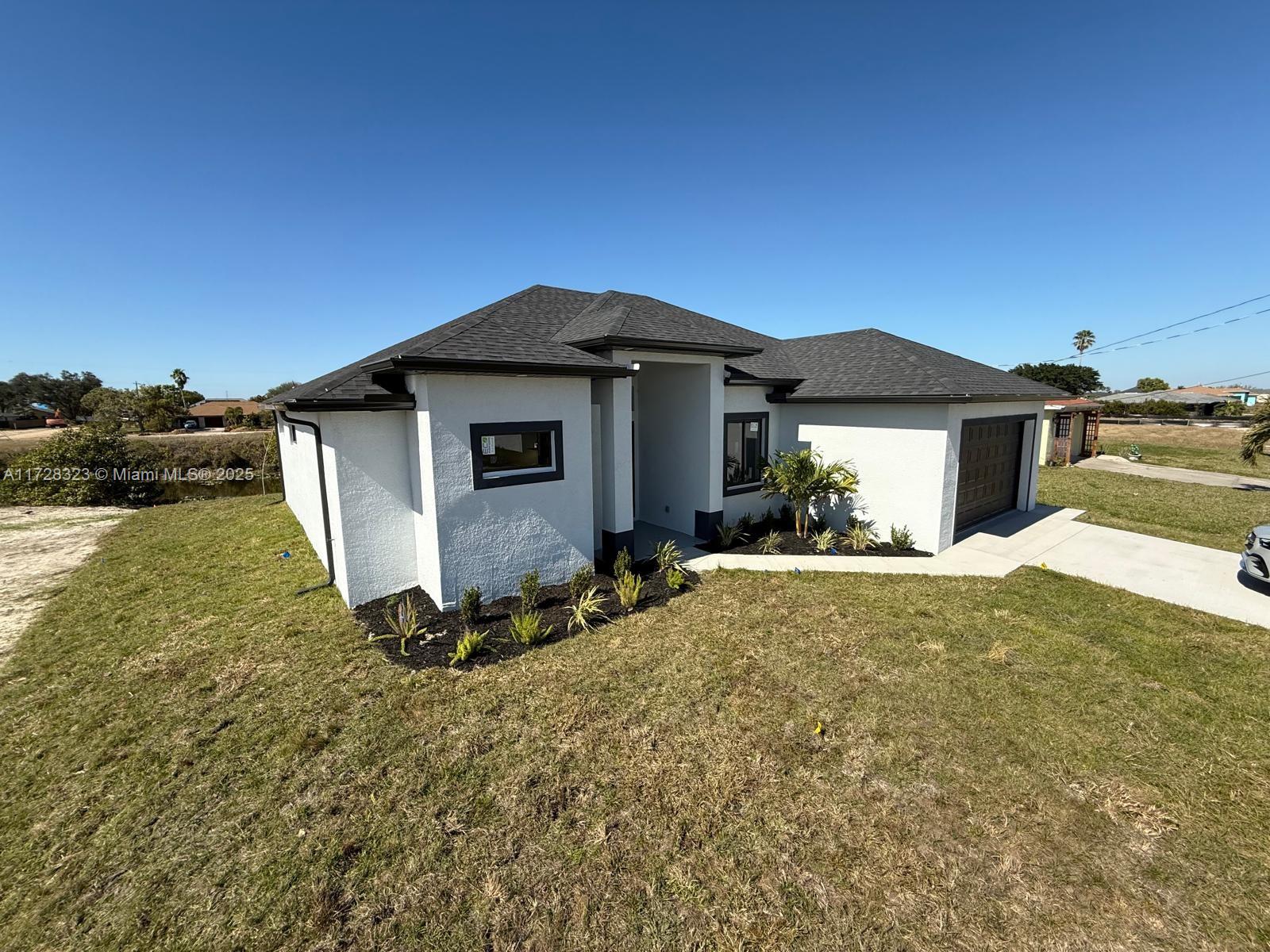A modern, white single-story house with a dark shingled roof and a concrete driveway — 1320 NE 14th  AVE, Cape Coral FL 33909, CAPE CORAL, FL