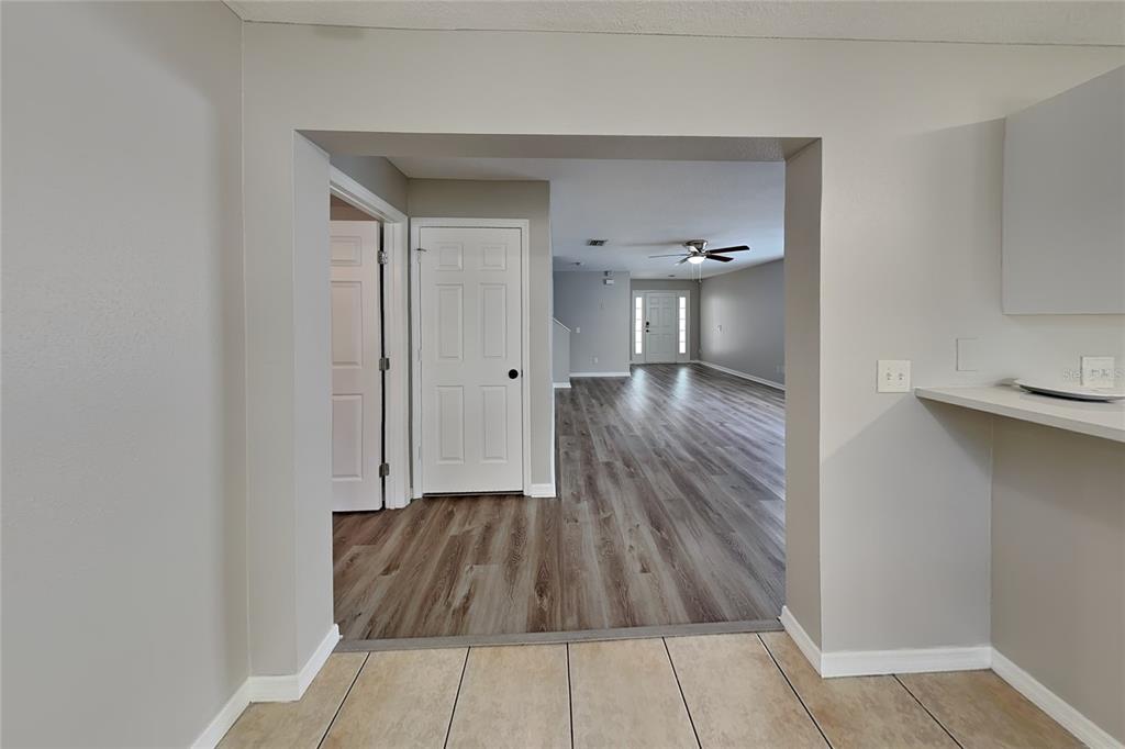 A view from a tiled room through a doorway into a living area with wood-look flooring — 32437 FISH HOOK LOOP, WESLEY CHAPEL, FL
