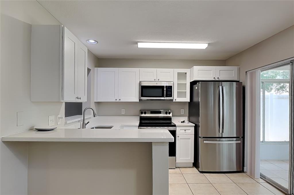 A kitchen features white cabinets, stainless steel appliances, and a breakfast bar with white countertops — 32437 FISH HOOK LOOP, WESLEY CHAPEL, FL