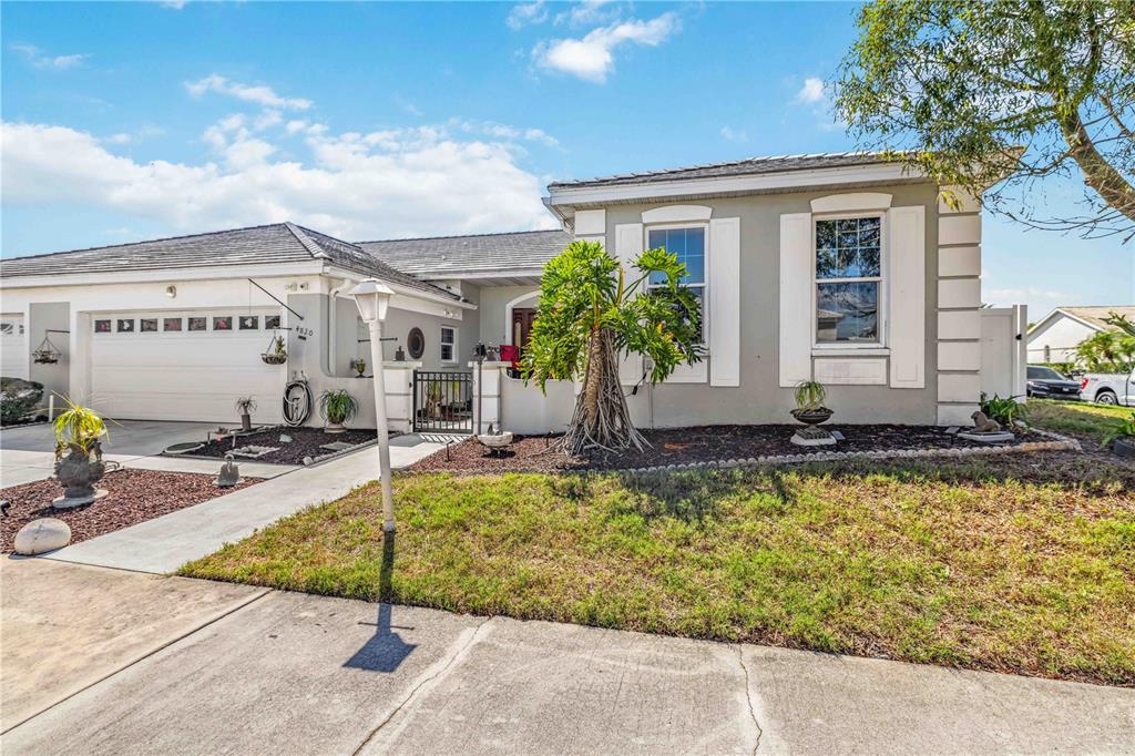 A single-story house with a two-car garage, gray stucco exterior, and a front yard — 4820 61ST AVENUE DRIVE W, BRADENTON, FL